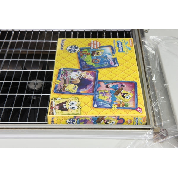 Shrink-wrapped game box on the mesh tray of the Maripak Compack 5800MC